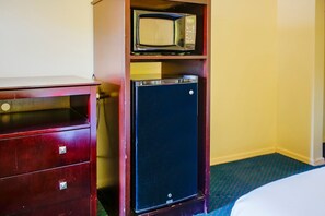 Una habitación compacta con un aparador de madera, un refrigerador pequeño y un microondas en un estante.