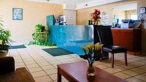 A reception area with a blue counter, a desk, a chair, and a plant.