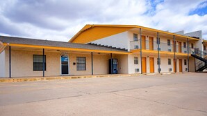 A two-story motel with a yellow awning, a front office, and a visible staircase to the upper level.