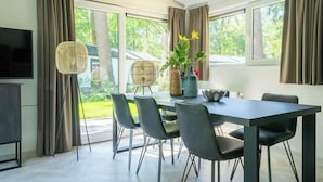 Een moderne eetruimte met een tafel, stoelen en een televisie.