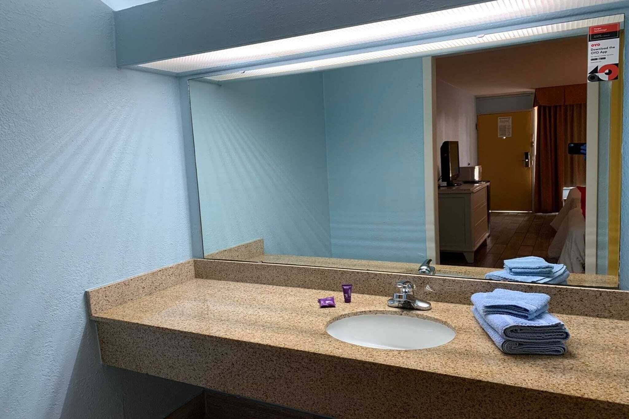 Un baño con encimera de granito, un lavabo, un espejo y un perchero para toallas.