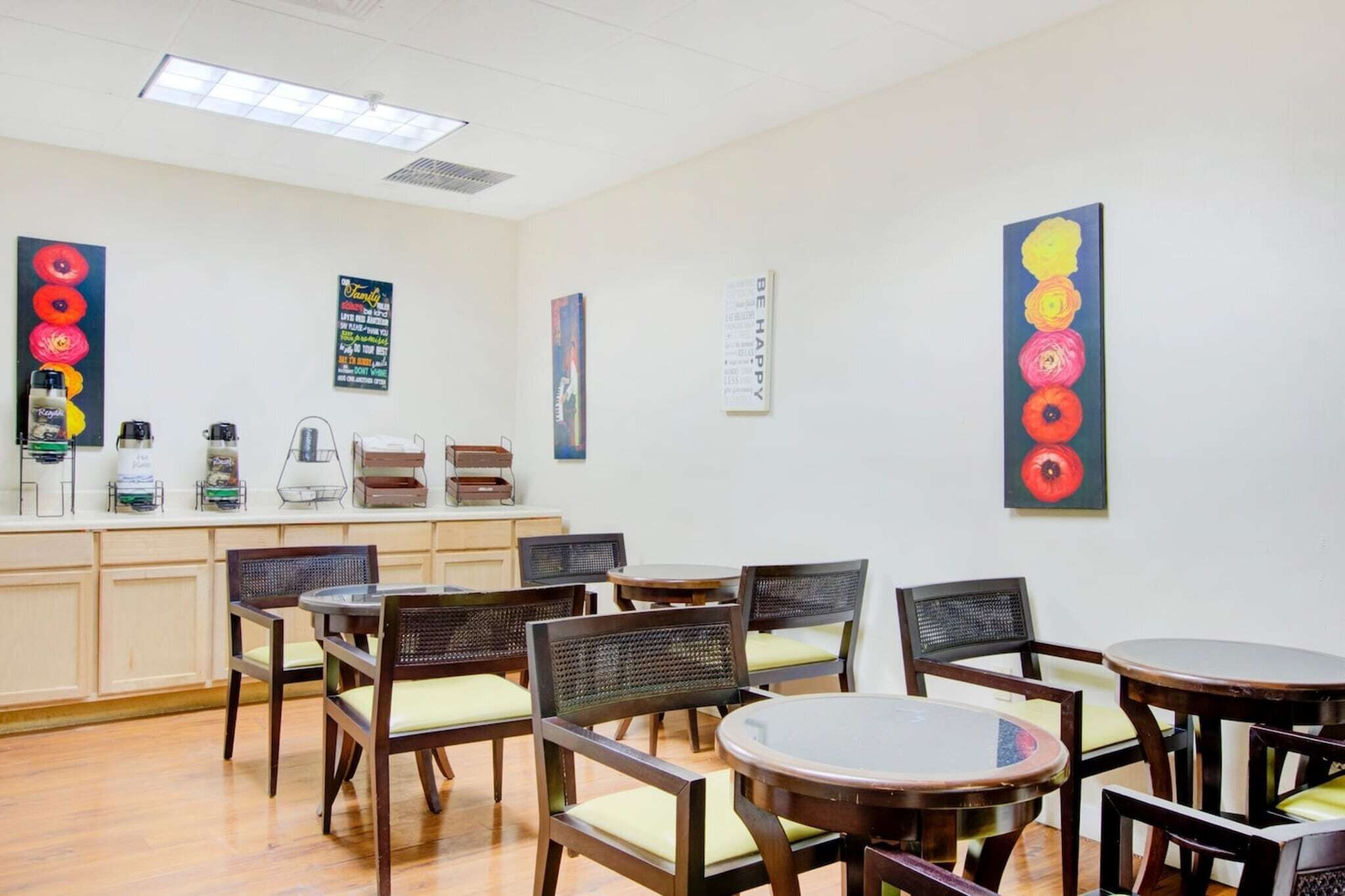 A dining area with wooden chairs and tables, a counter with various items, and wall art.