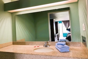 A bathroom with a sink, mirror, and towels.