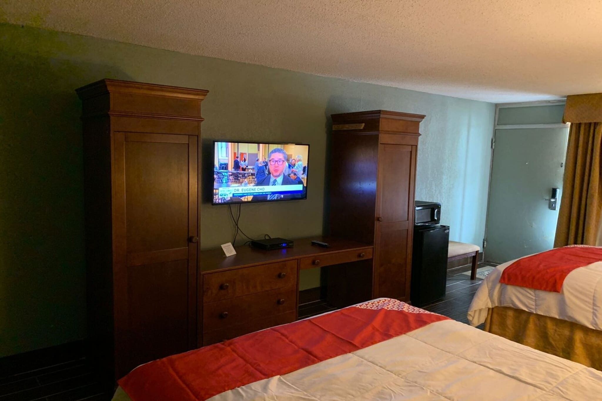 A hotel room with two beds, a TV on a desk, and a wardrobe.