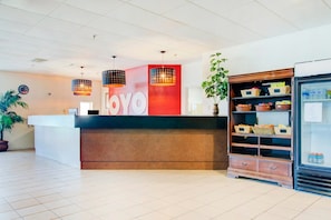 A reception desk with a 'YOYO' sign, a potted plant, a refrigerator with baskets, and a tiled floor.