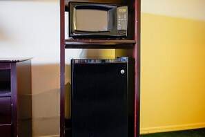 Un microondas y un refrigerador en una cocina con pared amarilla.