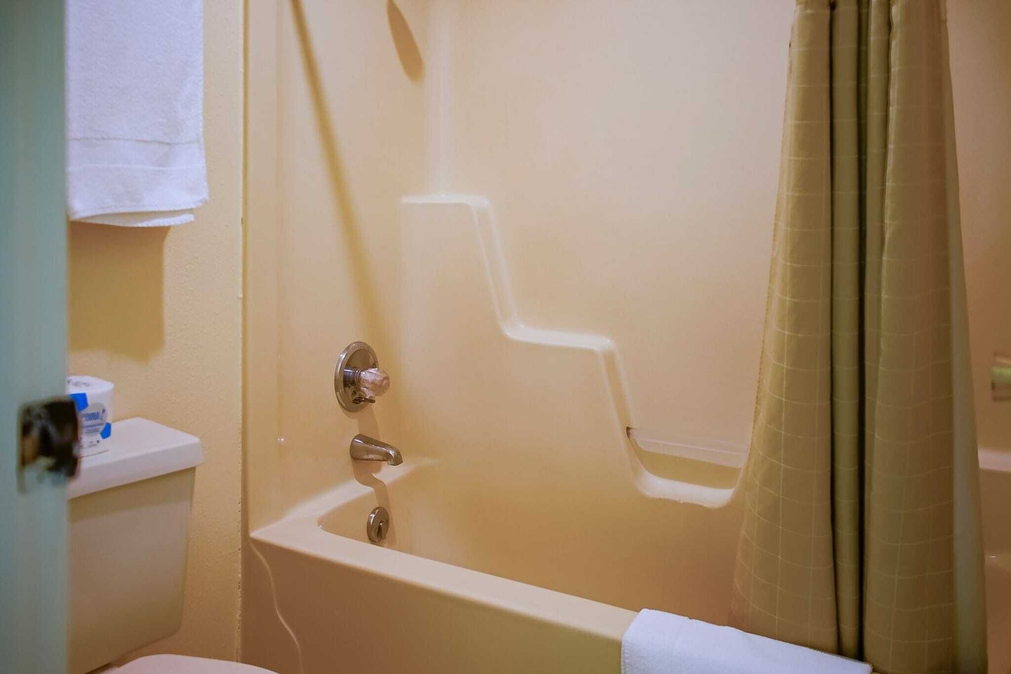 Une salle de bain avec une baignoire, des toilettes et une serviette accrochée au mur.