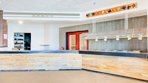 A reception area with a wooden reception desk, a coffee station, and a red door.