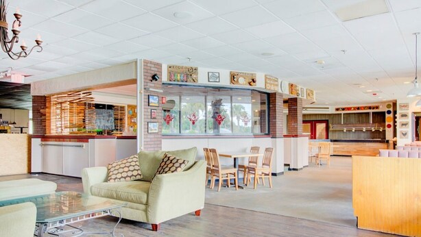 A spacious lobby with a seating area, a counter with a menu board, and a kitchen area in the background.