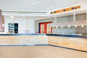 A reception area with a wooden reception desk, a wall-mounted coffee station, and a red door.