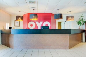 Una recepción con un gran letrero 'OYO', tres lámparas colgantes y una planta en maceta.