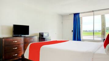 Une chambre d’hôtel équipée d’un lit, d’une télévision, d’une commode et d’une fenêtre donnant sur l’extérieur.