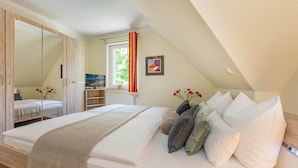 Een slaapkamer met een bed, een kledingkast, een raam met gordijnen en een schilderij aan de muur.