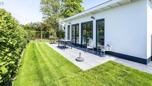 A modern house with a patio, a lawn, and a garden.
