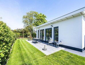 Ein modernes Haus mit Terrasse, Rasen und Garten.