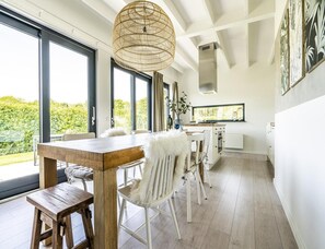 Eine moderne Küche mit weißen Schränken, einem Holzespeisetisch und einem großen Fenster mit Blick auf Grünflächen.