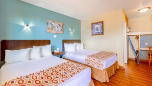 A hotel room with two beds, a desk, and a chair.