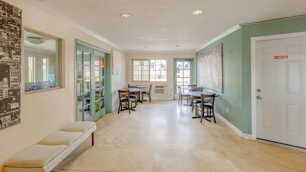A hallway with a bench, dining tables, chairs, and a door with a 'NO ADMITTANCE' sign.