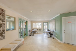 A hallway with a bench, dining tables, chairs, and a door with a 'NO ADMITTANCE' sign.