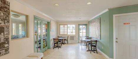 A hallway with a bench, dining tables, chairs, and a door with a 'NO ADMITTANCE' sign.