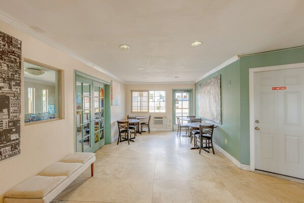 A hallway with a bench, dining tables, chairs, and a door with a 'NO ADMITTANCE' sign.