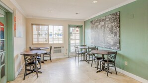 A dining area with tables and chairs, a large window, and a wall with a cityscape painting.