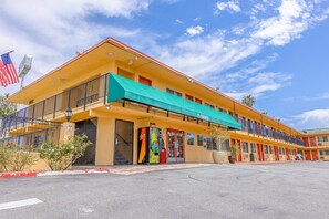 A motel with a green awning, a Coca-Cola vending machine, and an American flag. - King Bed Non-Smoking (Oceanside, CA)