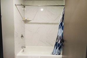 Une salle de bain avec une douche, un porte-serviettes et une étagÚre contenant des articles de toilette.