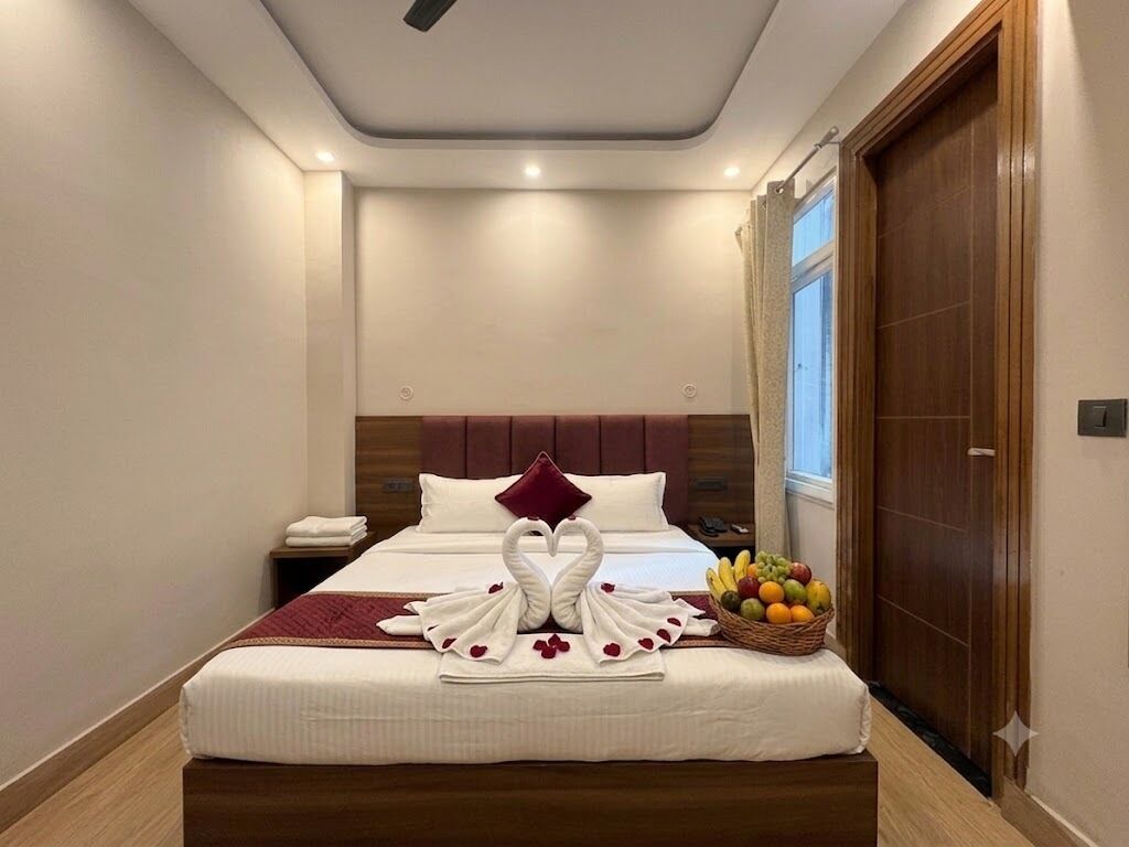 A hotel room with a neatly made bed, a fruit basket, and a wooden door.