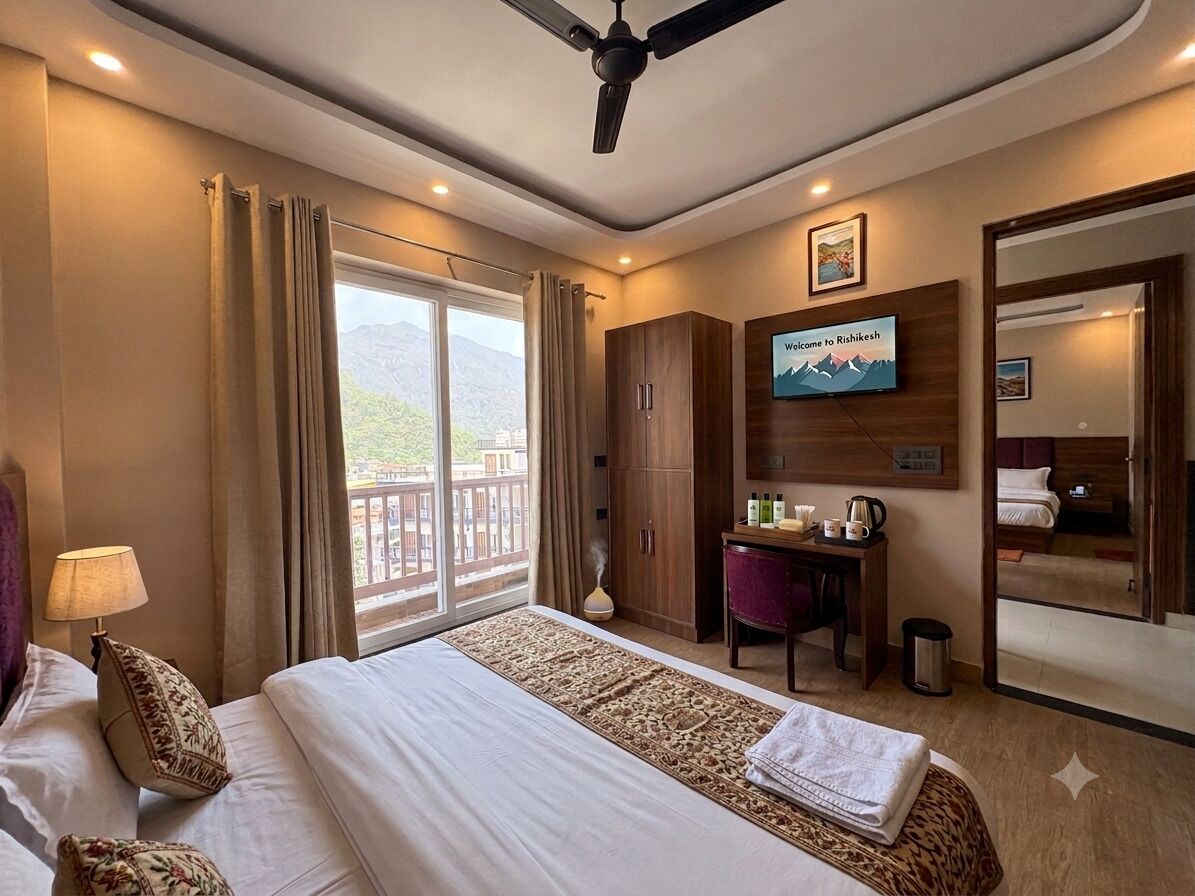 A hotel room with a bed, a desk, a television, and a view of the mountains.