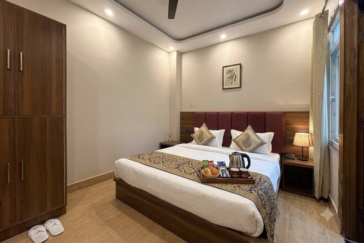 Una habitación de hotel con cama, mesita de noche, lámpara y armario.