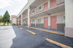 Un motel de varios pisos con estacionamiento, habitaciones individuales con acceso directo y un balcón en el piso superior.