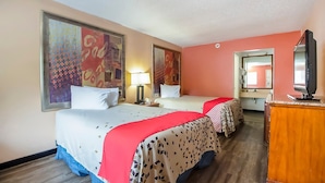 A hotel room with two beds, a desk, a television, and artwork on the walls.
