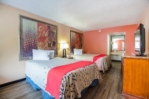 A hotel room with two beds, a desk, a television, and artwork on the walls.