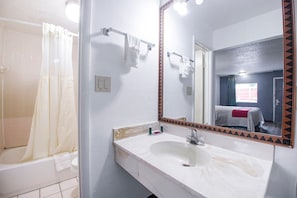 Un baño con bañera, lavabo, espejo y cortina de ducha.
