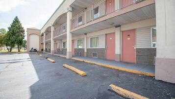 A multi-story motel with a parking lot, individual rooms with doors, and a balcony on the upper floor.