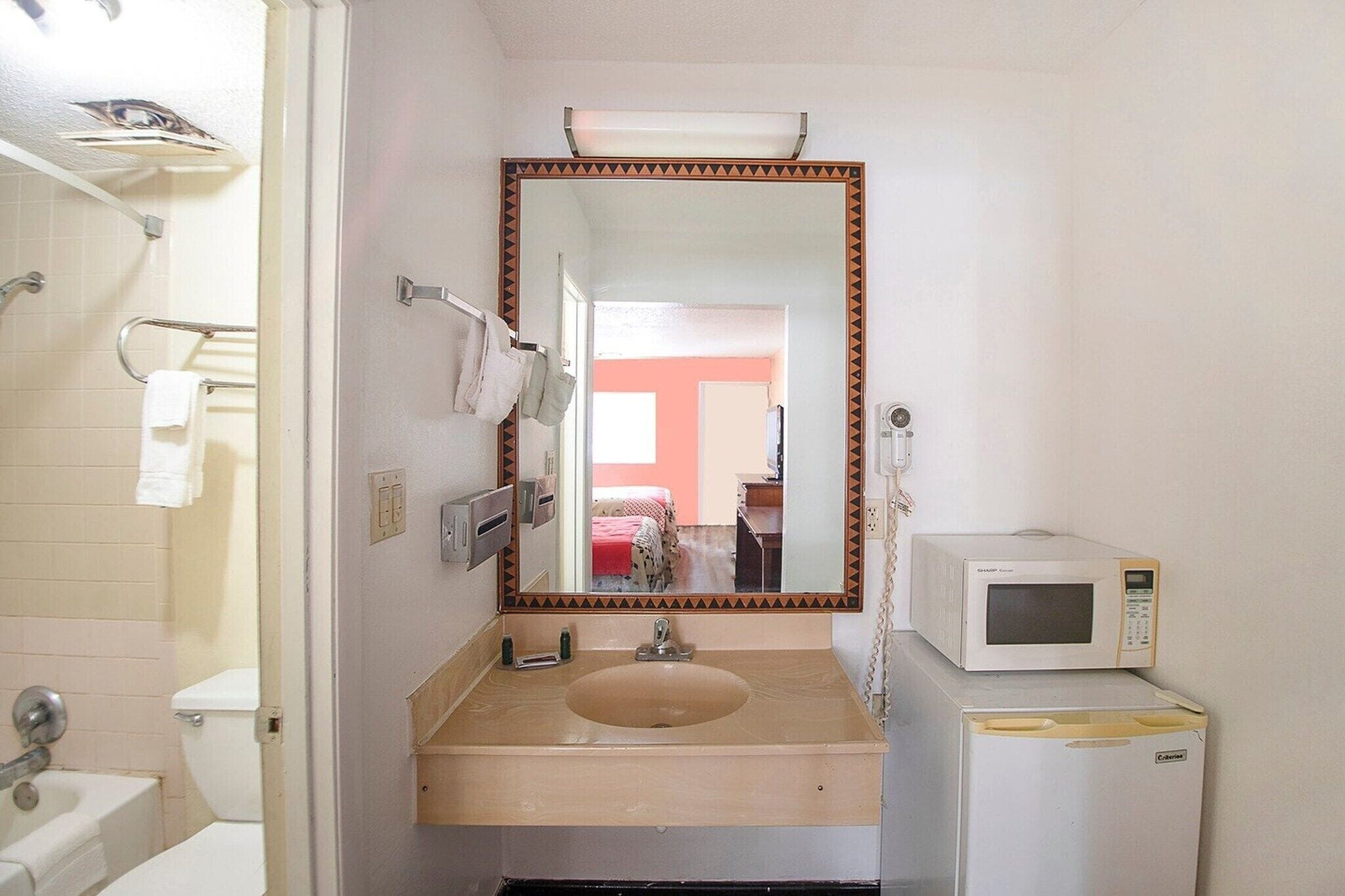 Une salle de bain équipée d’un lavabo, d’un miroir, de toilettes et d’un four à micro-ondes.