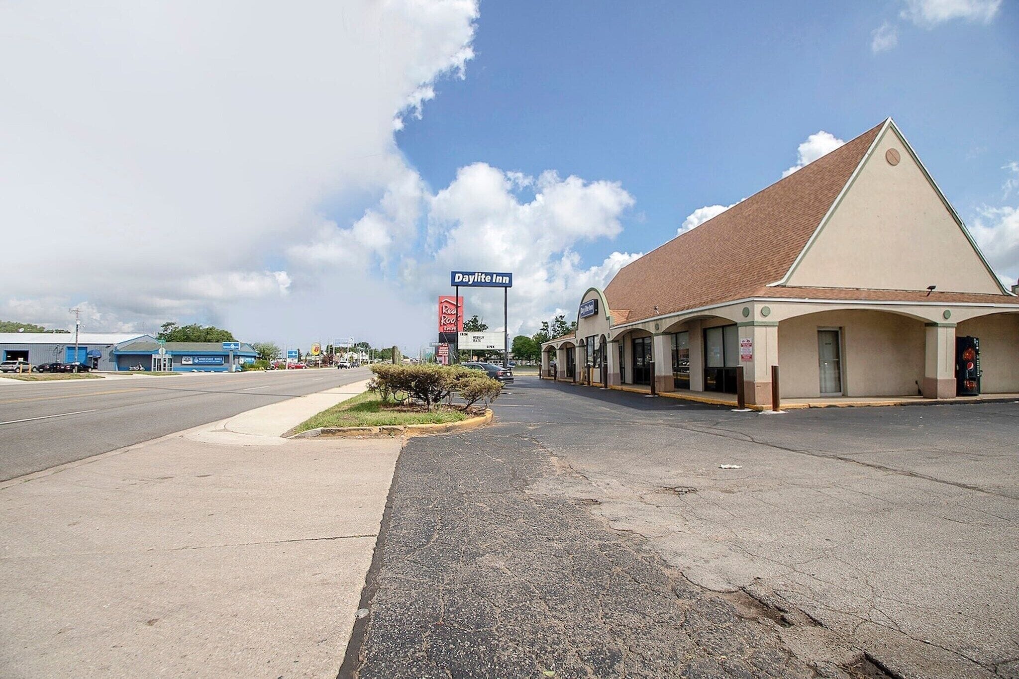 A Daylite Inn with a single-story structure, a parking lot, and a clear sky.