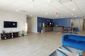 A spacious lobby with a reception desk, seating area, and a television mounted on the wall.