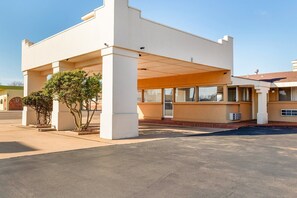 A modern building with a covered entrance, large windows, and a parking area.