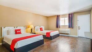 Ein Hotelzimmer mit zwei Betten, einem Schreibtisch, einem Fenster mit Vorhängen und einer Klimaanlage.