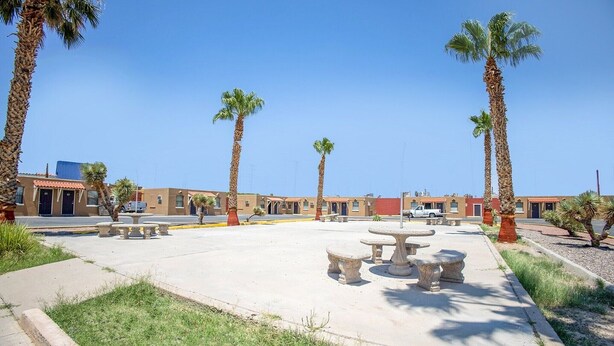 Un patio con palmeras, asientos al aire libre y un edificio de techo rojo.