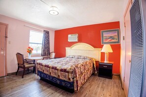 Une chambre à coucher avec un lit, un bureau, une chaise, une fenêtre et une porte.