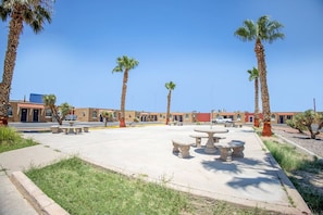 Un patio con palmeras, asientos al aire libre y un edificio de techo rojo.