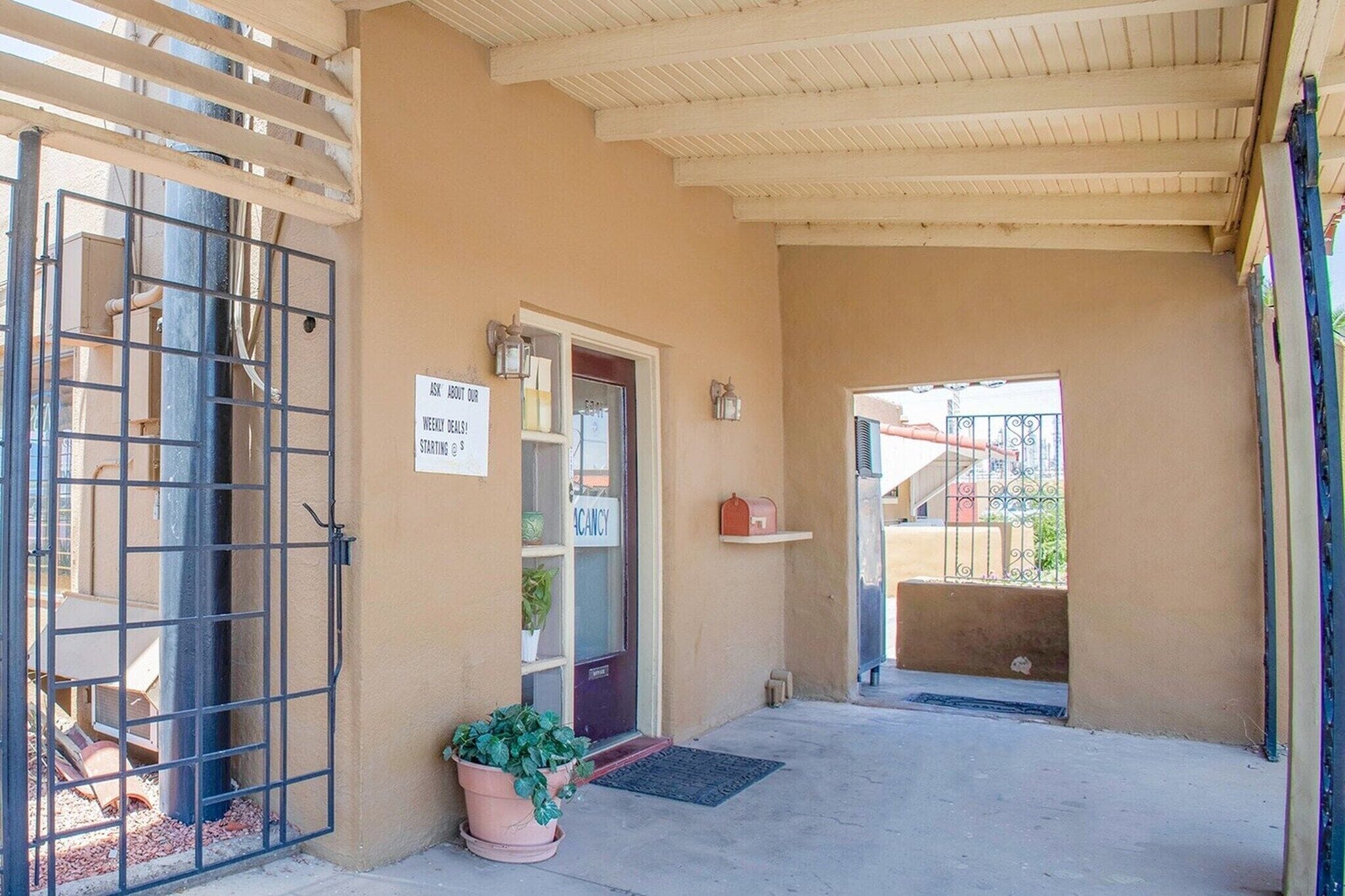 A building entrance with a metal gate, a door with a 'VACANCY' sign, and a potted plant.
