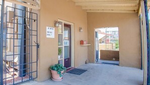 Entrada de un edificio con una reja metálica, una puerta con el letrero 'VACANCY' y una planta en maceta.
