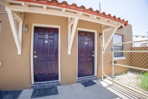 A building with two dark-colored doors, a beige exterior, and a red-tiled roof.