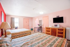 Quarto de hotel com duas camas, uma escrivaninha, uma cadeira, televisão, micro-ondas e frigorífico.