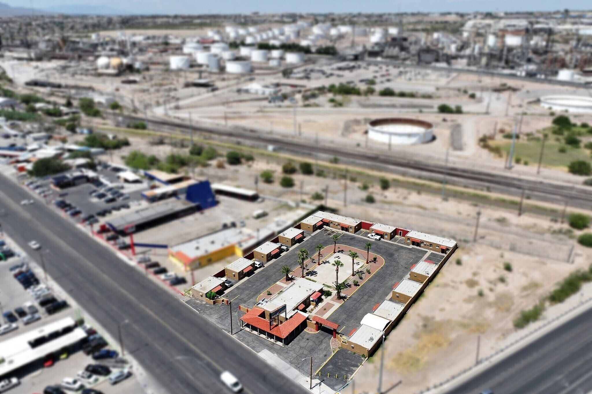 Vista aérea de um estacionamento com várias fileiras de carros estacionados e uma área aberta central.