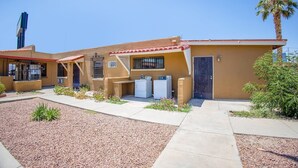 A building with a flat roof, a door, and a small garden area with plants. - King Bed Non-Smoking (El Paso TX)